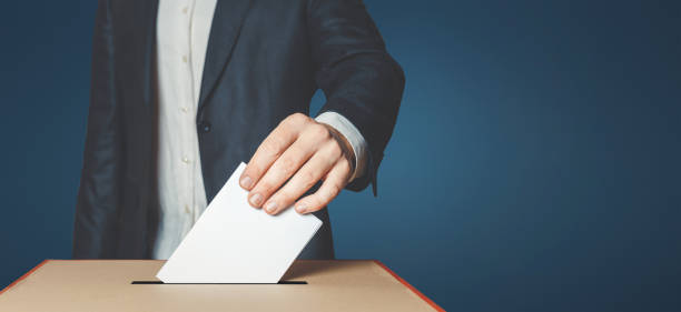 unrecognizable-male-voter-holds-in-his-hand-a-ballot-above-the-ballot-box